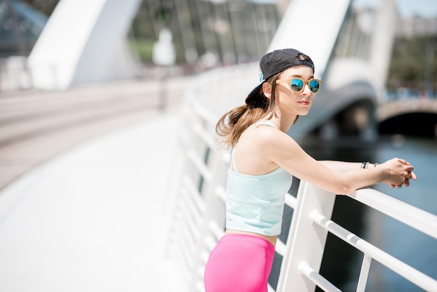 Portrait of a woman in sportswear standing on the modern bridge in Lyon city