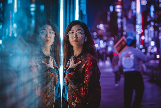portrait of woman standing against illuminated city at night