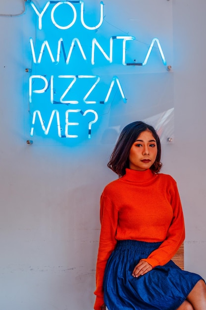 Portrait of woman standing against illuminated text on wall