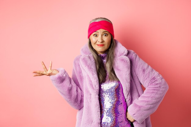 Portrait of woman standing against pink background