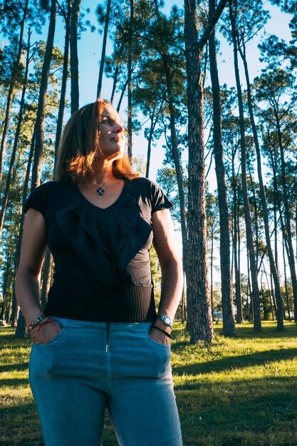 Portrait of woman standing against tall trees