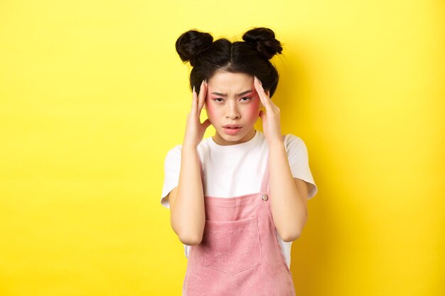 Portrait of woman standing against yellow background