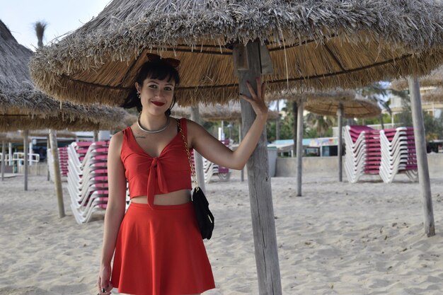 Portrait of woman standing at beach under thatched roof