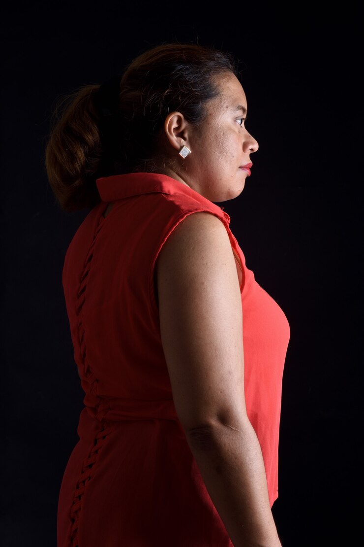 Portrait of a woman standing on black background, side view