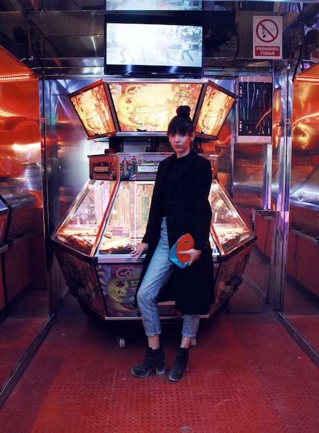 Foto ritratto di una donna in piedi vicino a un gioco arcade in un parco divertimenti