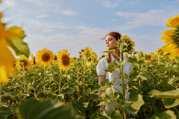 Portrait of woman standing by flowering plants on field