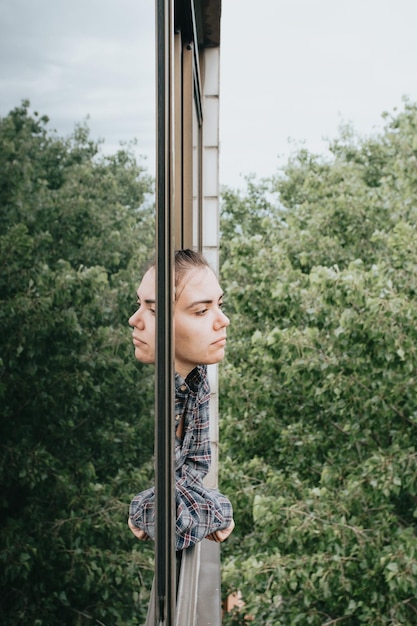 Photo portrait of woman standing by window against trees