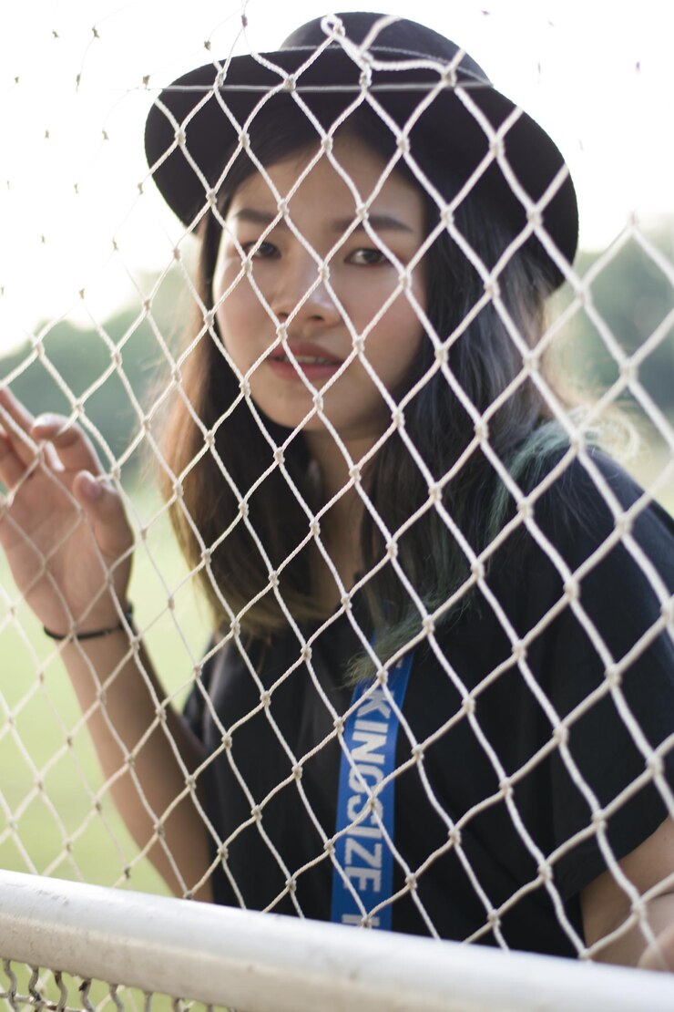 Photo 체인링크 울타리 뒤 에 서 있는 여자 의 초상화