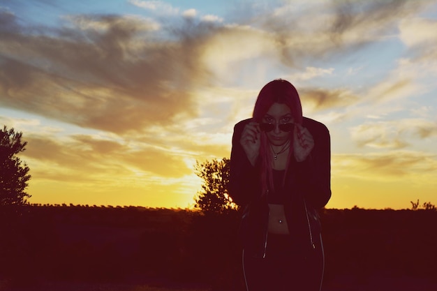 Foto ritratto di una donna in piedi sul campo contro il cielo durante il tramonto
