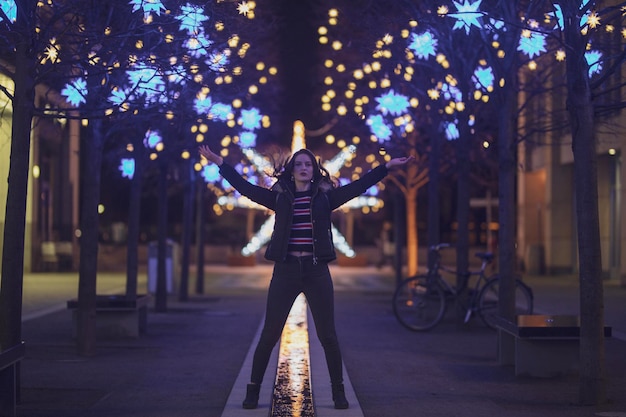Foto ritratto di una donna in piedi sul marciapiede contro le luci illuminate di notte