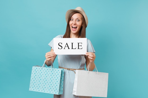 Photo portrait of woman in summer dress, straw hat holding packages bags with purchases after shopping, empty blank say cloud, speech bubble card isolated on blue pastel background. copy space advertisement