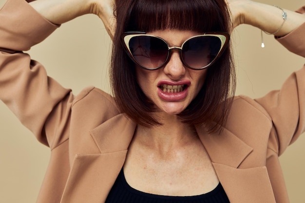 Portrait of a woman in sunglasses short haired suit gesturing with hands light background