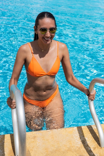 Portrait woman at swimming pool ladder