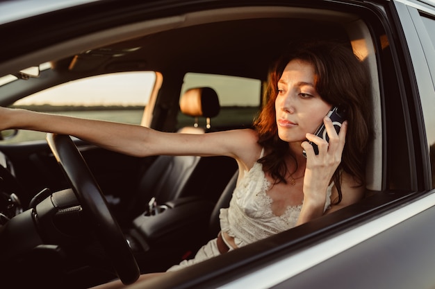 彼女の車を運転しながら携帯電話で話している女性の肖像画