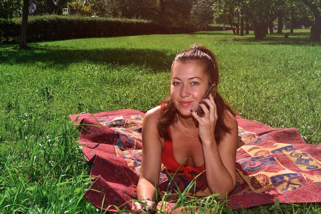 Portrait of woman talking on phone while lying at park
