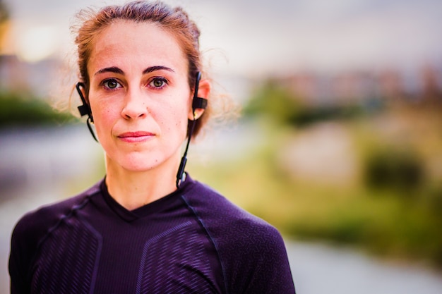 Portrait of a woman training cardio outside listening music