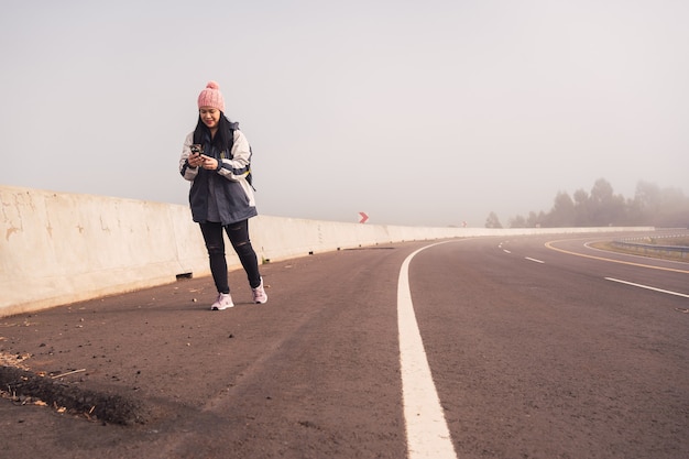 Ritratto di una viaggiatrice che cammina e tiene in mano uno smartphone.