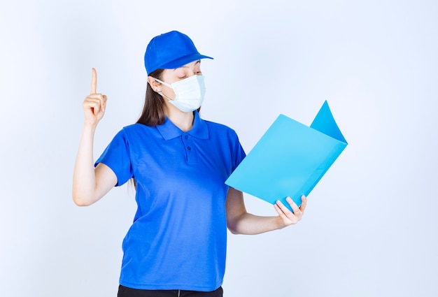 Portrait of woman in uniform and medical mask holding folder