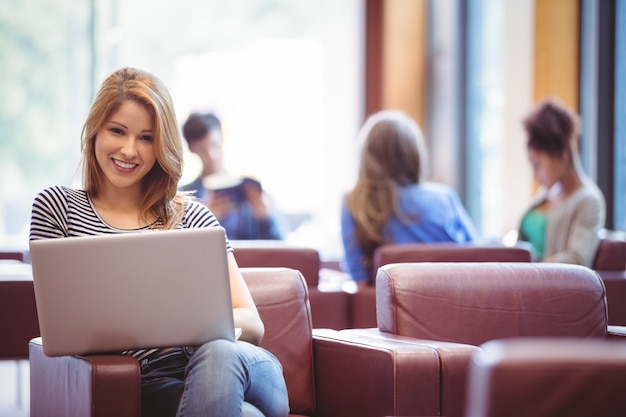 Portrait of a woman using her laptop and smiling at camera