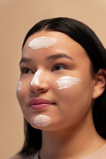 Photo portrait of woman using moisturizer on face