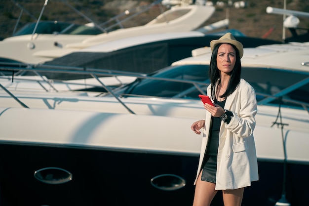 Portrait of woman using phone standing against yacht