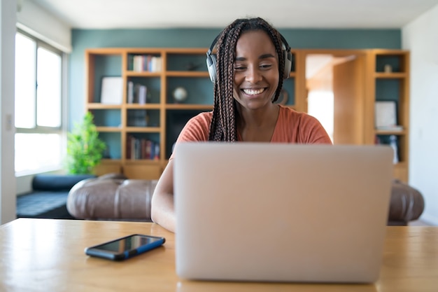 Portrait of a woman on a video call with laptop and headphones while working from home. Home office concept