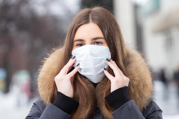전염병으로부터 보호하기 위해 보호 마스크를 쓰고 겨울에 거리를 걷는 여성의 초상화 감기로부터 보호 독감 대기 오염 건강 개념
