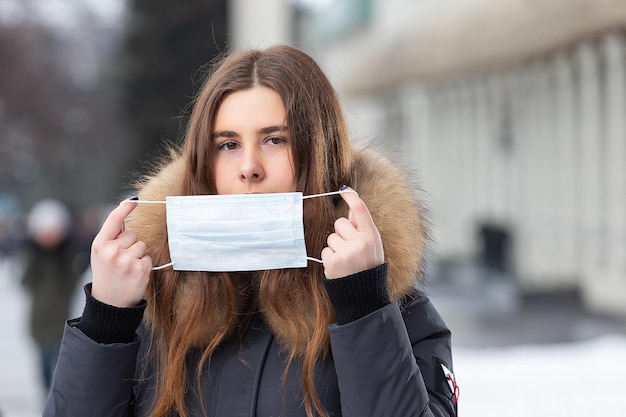 感染症から保護するために保護マスクで冬に通りを歩いている女性の肖像風邪インフルエンザ大気汚染からの保護健康の概念