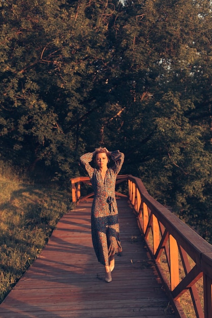 Portrait of woman walking on footbridge against trees