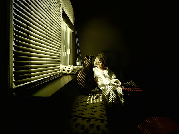 Foto ritratto di una donna che indossa un accappatoio mentre è seduta a casa