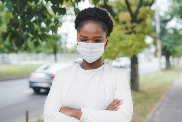 Ritratto di donna che indossa la maschera di sicurezza covid19 guardando la fotocamera all'aperto per strada malattia epidemica del virus nuova normalità in tempi di coronavirus a causa della pandemia covid19