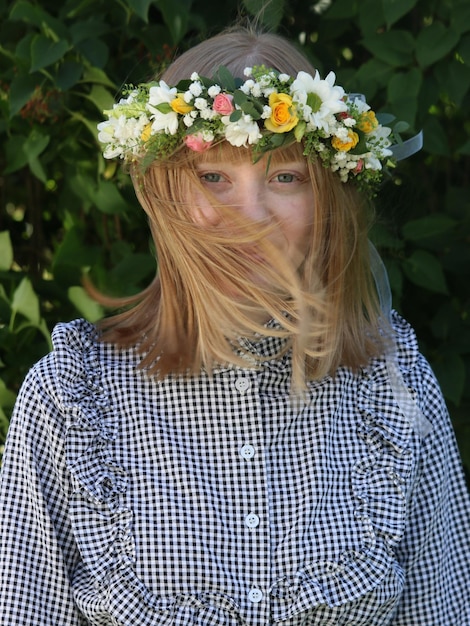 Photo portrait of woman wearing flowers standing against plants in park