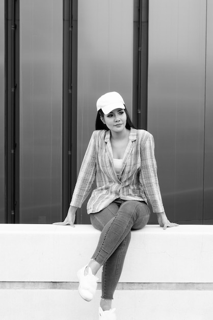 Photo portrait of woman wearing hat sitting against wall