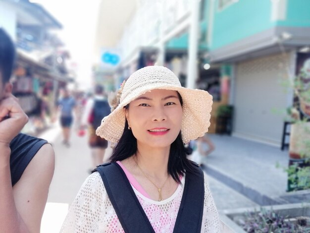 Portrait of woman wearing hat while standing on city street