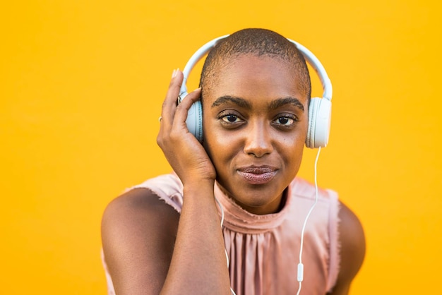 portrait of woman wearing headphones against yellow background