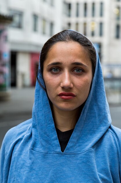 Foto ritratto di una donna con il cappuccio in piedi contro un edificio in città