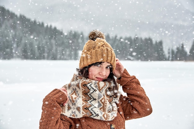 portrait of woman wearing knit hat standing in snow