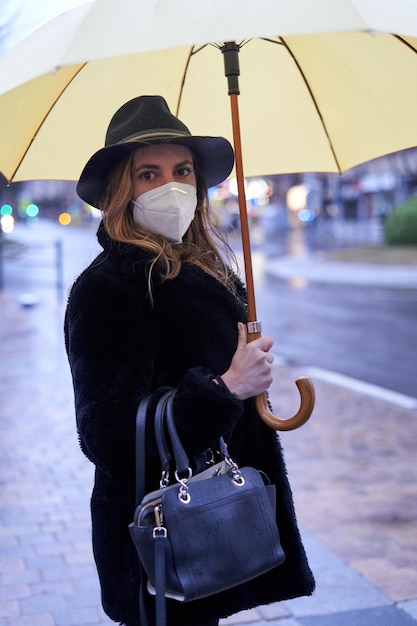 Foto ritratto di una donna che indossa una maschera e tiene un ombrello