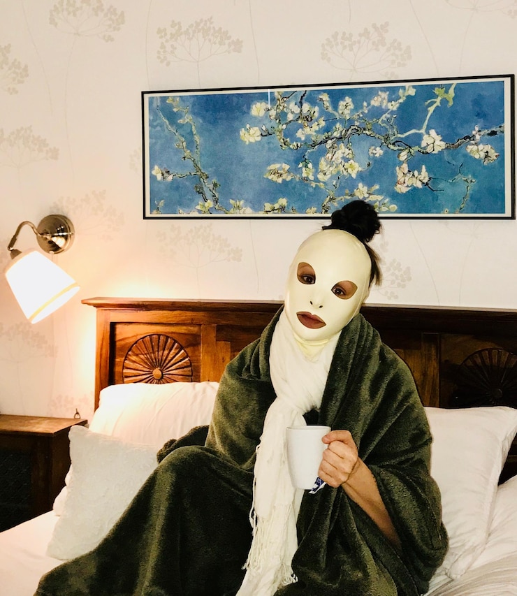 Photo portrait of woman wearing mask sitting on bed at home