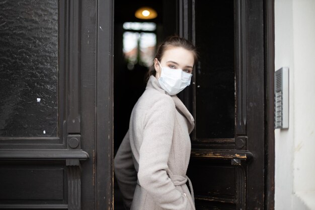 Portrait of woman wearing mask standing at doorway