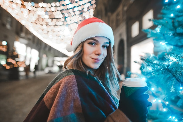 portrait woman wearing Santa hat holding cup of coffee