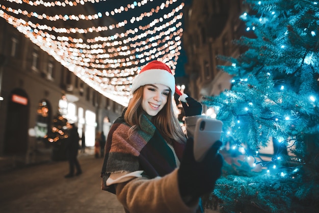 Photo portrait woman wearing santa hat taking selfie