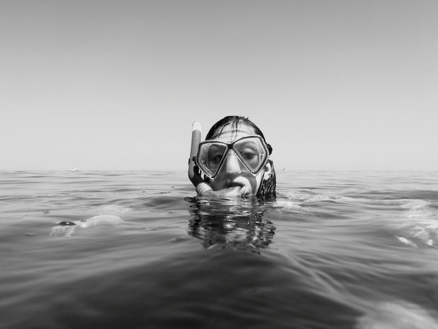 Foto ritratto di una donna che indossa una maschera da immersione mentre nuota in mare