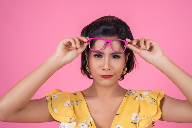 Photo portrait of woman wearing sunglasses against pink background