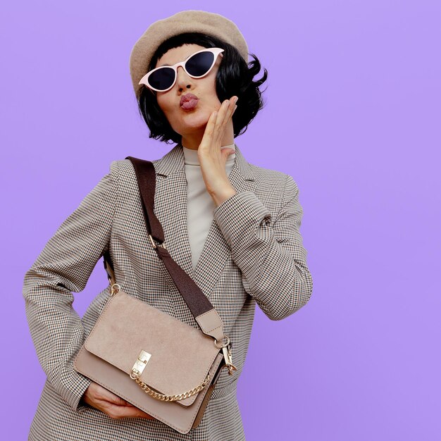 Portrait of woman wearing sunglasses standing against purple background