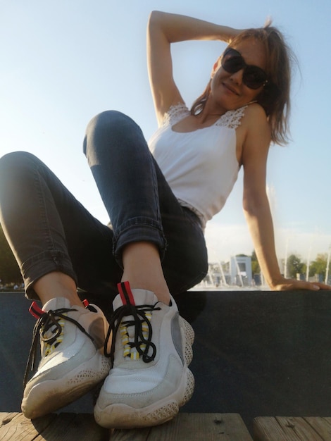 Portrait of woman wearing sunglasses while sitting on land against sky