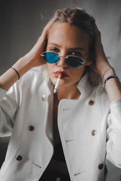 Portrait of woman wearing sunglasses while smoking cigarette