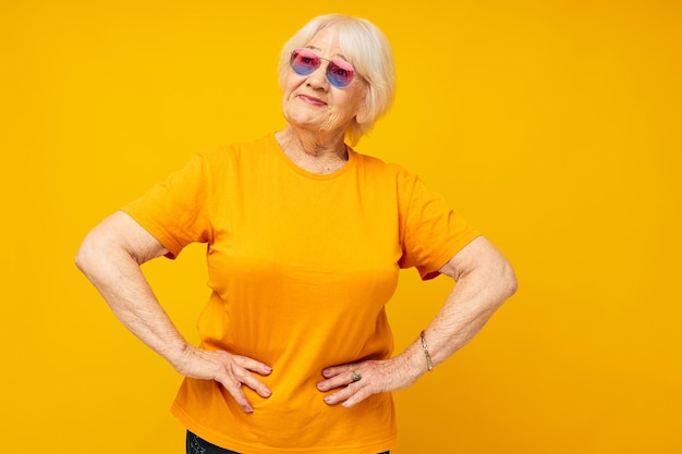 Foto ritratto di una donna che indossa occhiali da sole in piedi su uno sfondo giallo