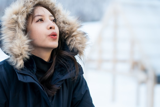 Portrait of woman wearing warm coat with fur hood, having fun in winter