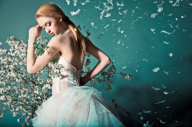 Portrait of a woman in wedding dress behind the branches with flowers